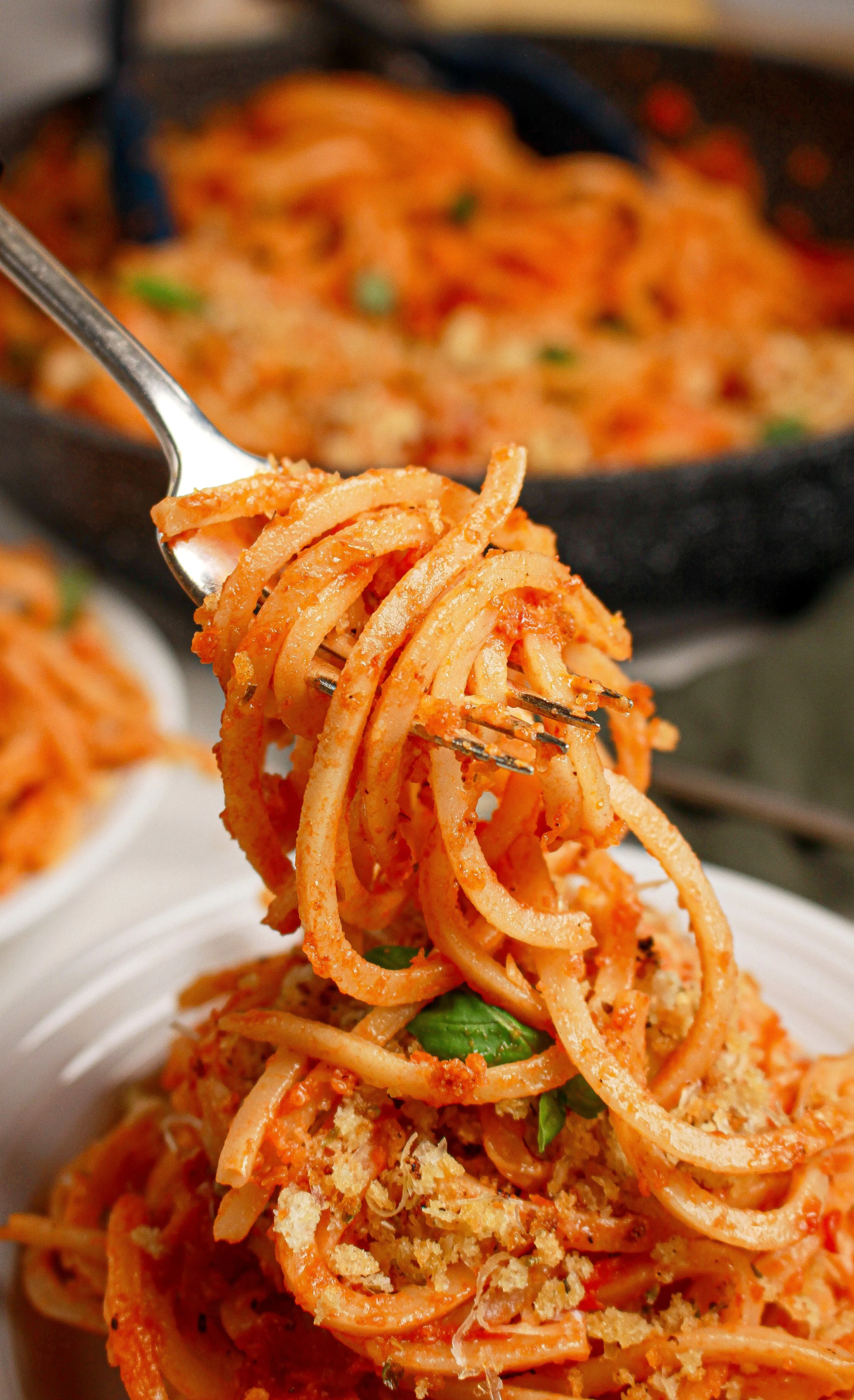 Fork holding spaghetti with tomato sauce, basil, and grated cheese