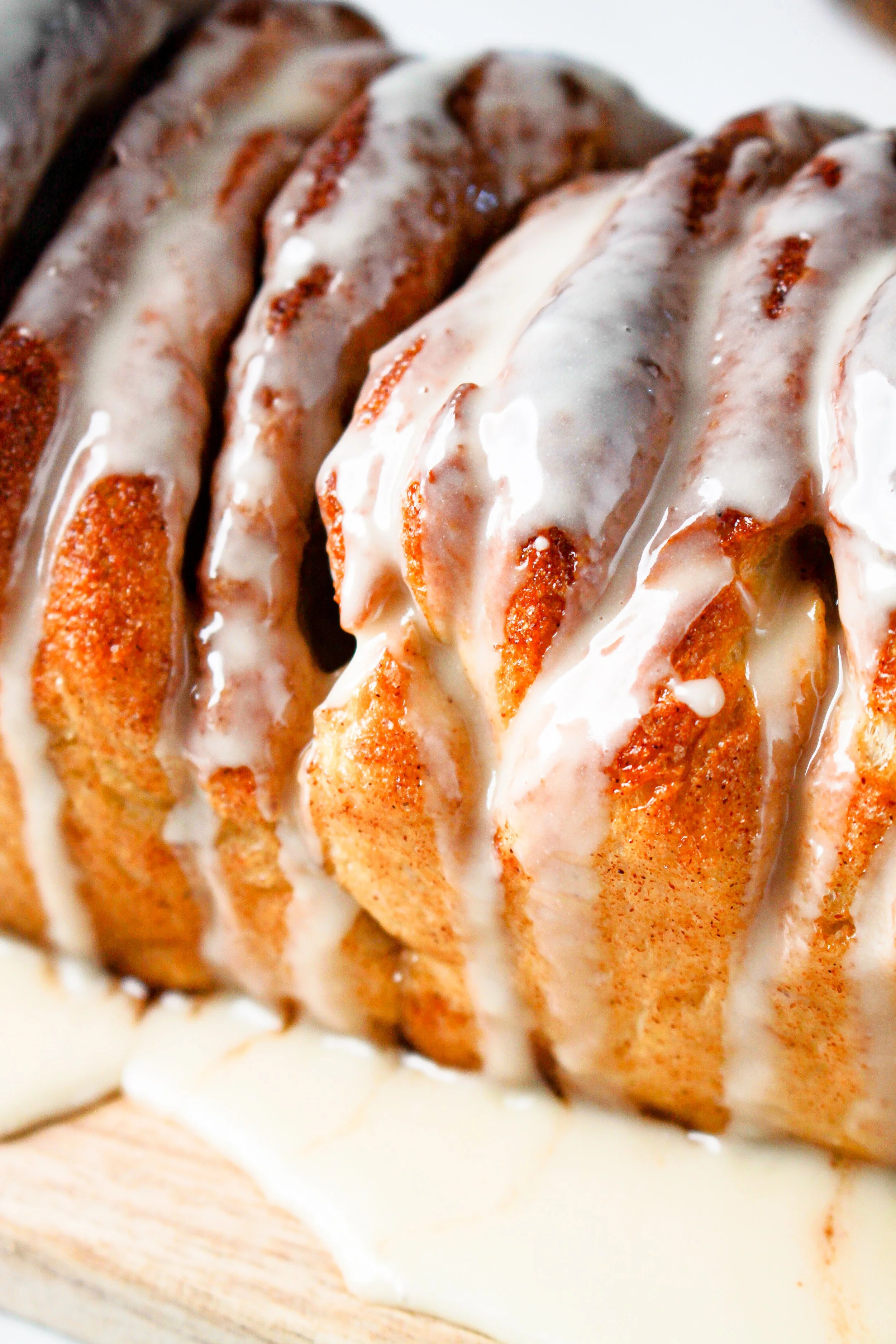 A close-up of a freshly baked cinnamon roll with white glaze