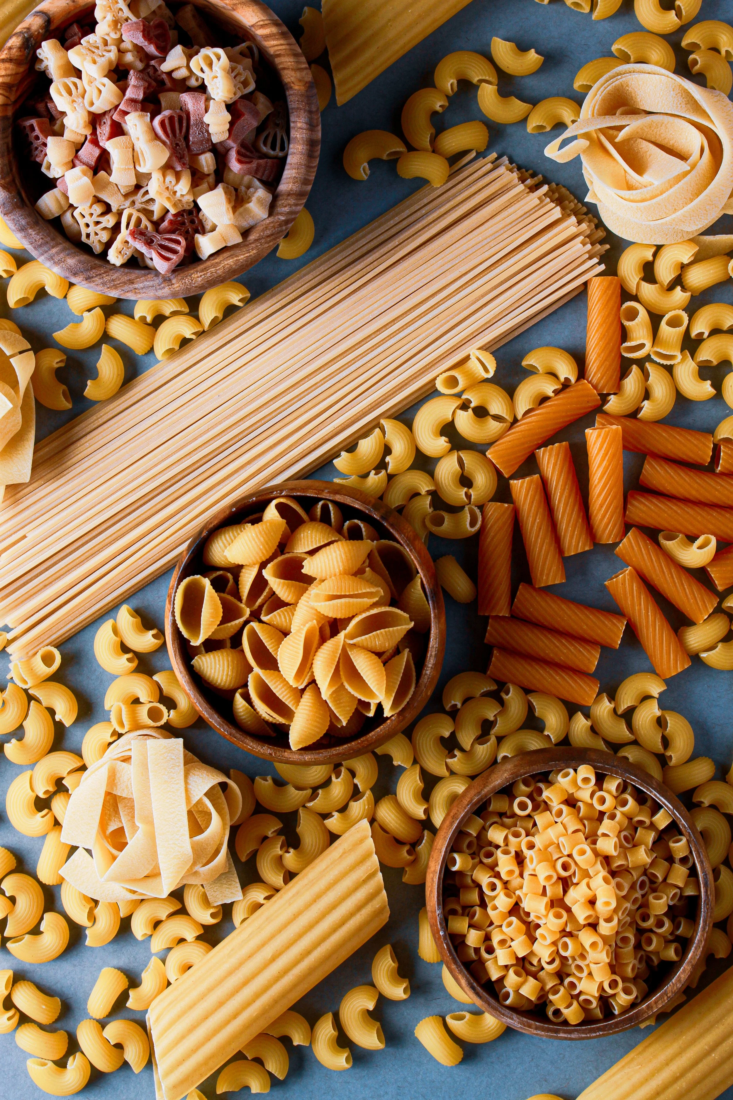 Assorted uncooked pasta including fusilli, penne, rigatoni, and linguine
