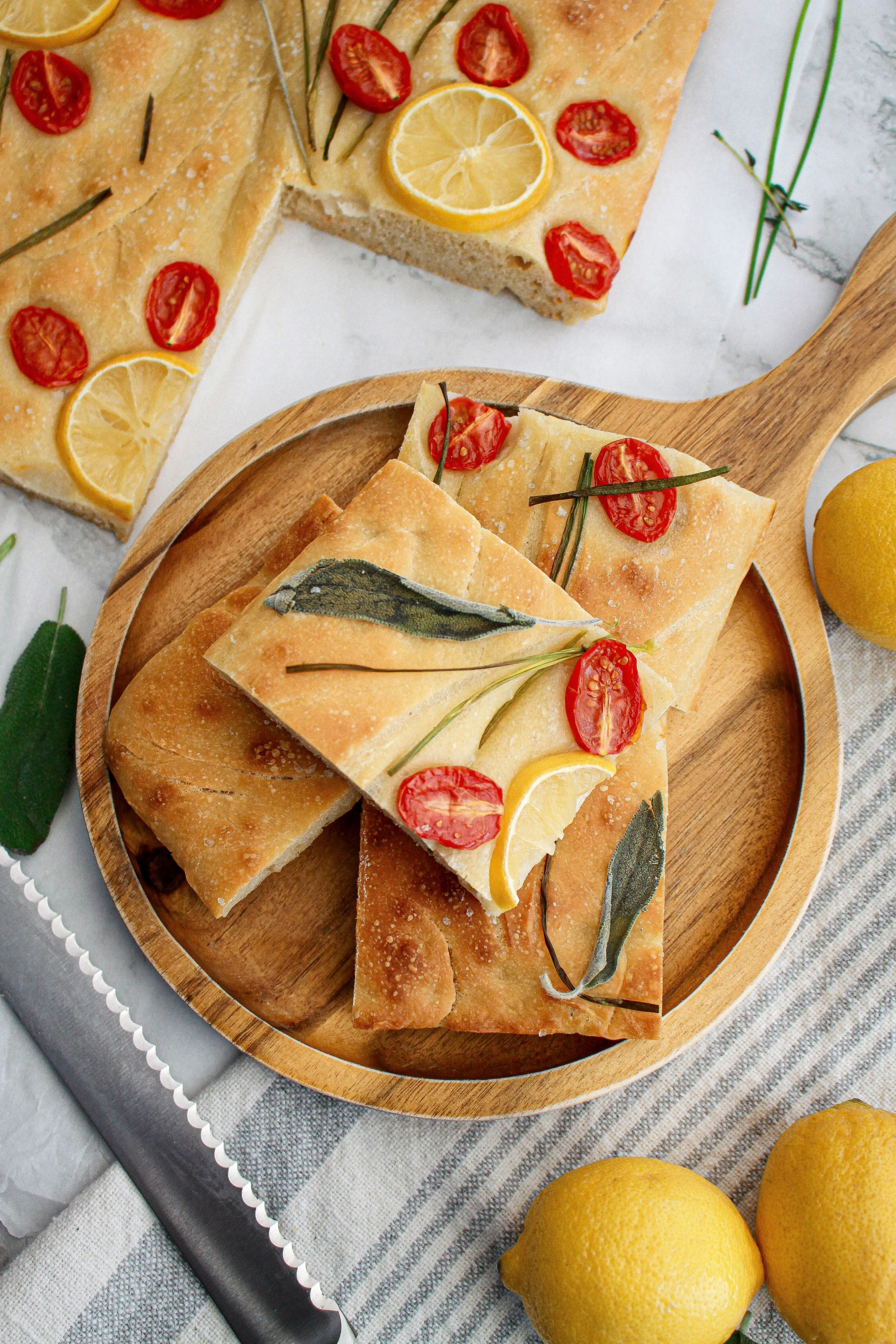 Focaccia bread with cherry tomatoes, lemon slices, and herbs